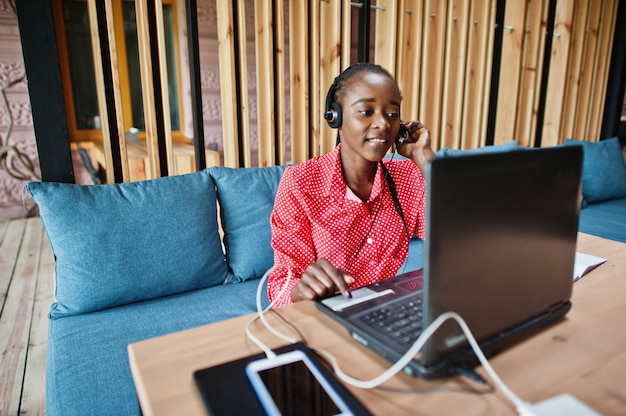 La giovane donna lavora in un operatore di call center e un agente del servizio clienti che indossa cuffie con microfono che lavorano su laptop