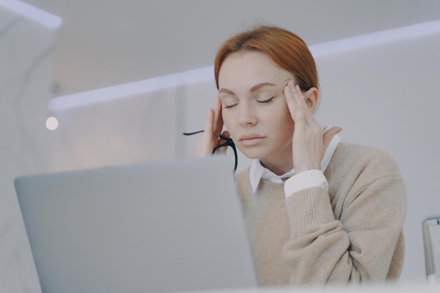 La giovane donna malata ha dolore alle tempie in ufficio Il dipendente ha mal di testa sul posto di lavoro