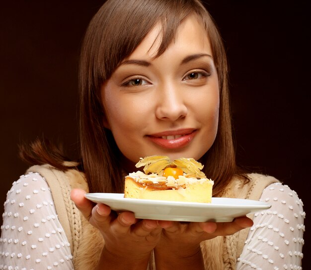 La giovane donna mangia una torta dolce