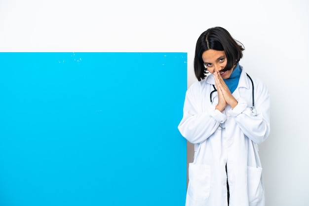La giovane donna medico di razza mista con un grande cartello isolato su sfondo bianco tiene insieme il palmo. La persona chiede qualcosa