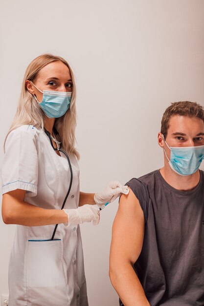 La giovane donna medico fa una vaccinazione per iniezione al paziente nel braccio