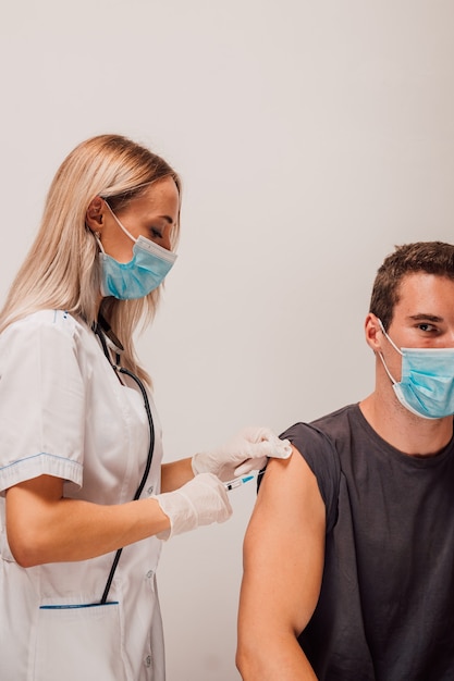 La giovane donna medico fa una vaccinazione per iniezione al paziente nel braccio