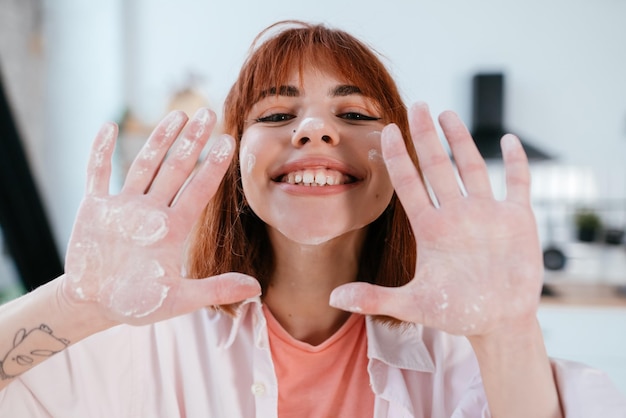 La giovane donna mostra le sue mani nella farina in cucina