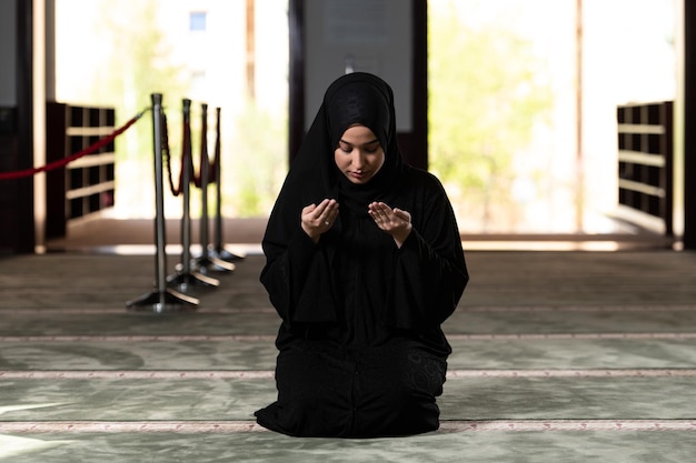 La giovane donna musulmana sta pregando nella moschea