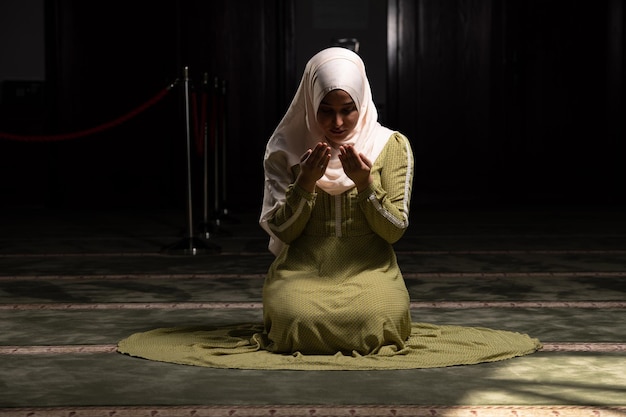 La giovane donna musulmana sta pregando nella moschea