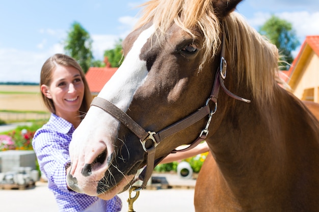 La giovane donna nella stalla con cavallo ed è felice