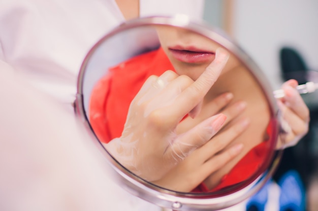 La giovane donna ottiene un'iniezione nelle sue labbra nel salone di bellezza. Iniezioni di bellezza - Donna che giace nell'ufficio dell'estetista. Aumenta le labbra con acido ialuronico, procedura di contouring, rivitalizzazione