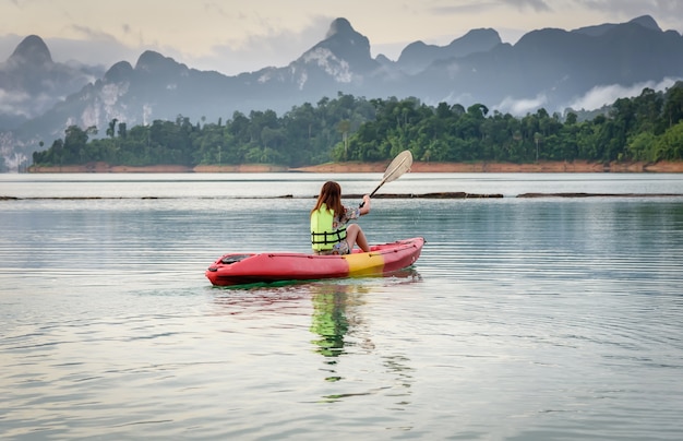 La giovane donna pagaia un kajak sulla laguna, Kayaking sul bacino idrico naturale