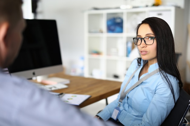 La giovane donna parla con un uomo sul posto di lavoro