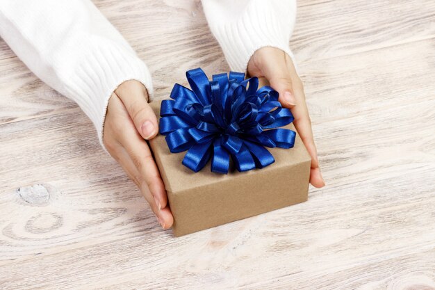 La giovane donna passa il contenitore di regalo della tenuta con il nastro blu