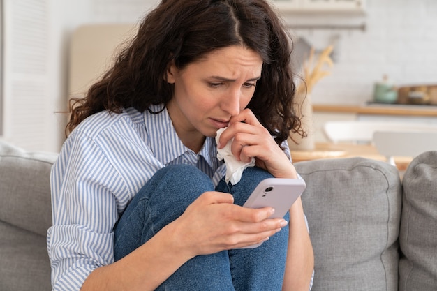 La giovane donna piange e legge le cattive notizie sullo smartphone