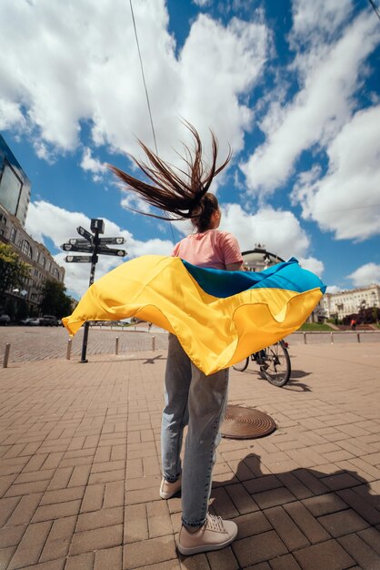 La giovane donna porta la bandiera dell'Ucraina che sventola dietro di lei