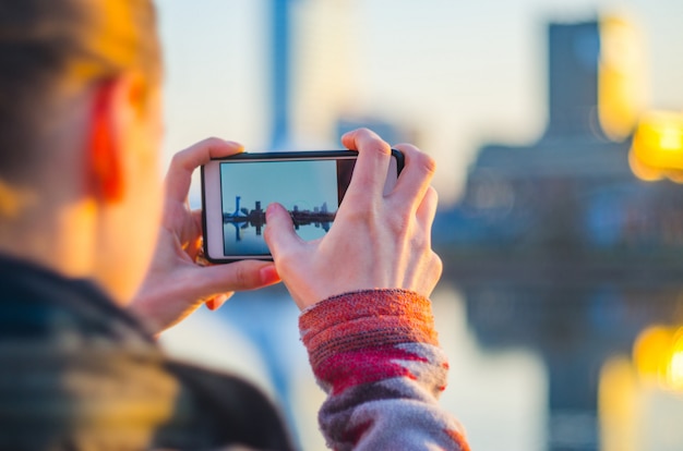 La giovane donna prende le immagini della città su uno smartphone