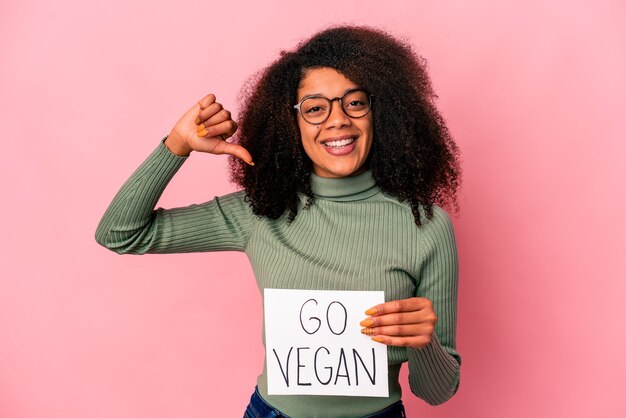 La giovane donna riccia afroamericana che tiene un cartello vegano si sente orgogliosa e sicura di sé, esempio da seguire.