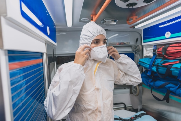 La giovane donna sanitaria indossa una tuta protettiva contro i virus in un'ambulanza