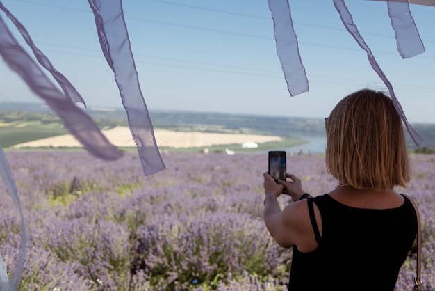 La giovane donna scatta una foto di un campo di lavanda sul suo telefono