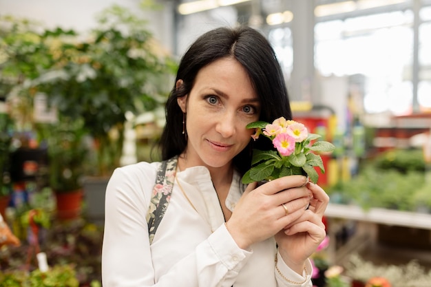 La giovane donna sceglie le piante d'appartamento in un negozio di fiori