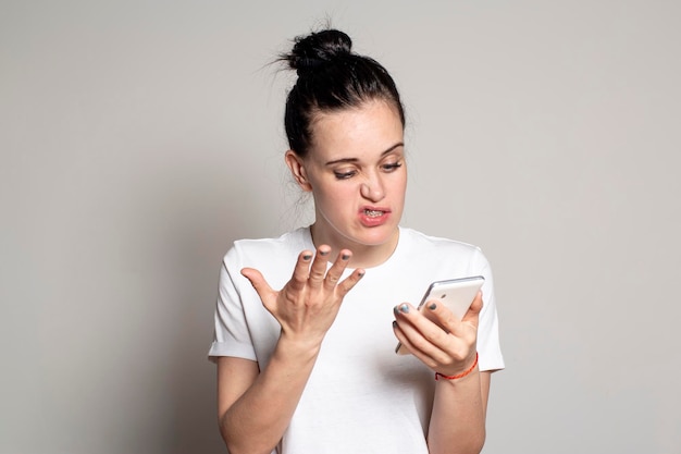 La giovane donna sconvolta guarda il suo smartphone vede cattive notizie o le foto si arrabbiano