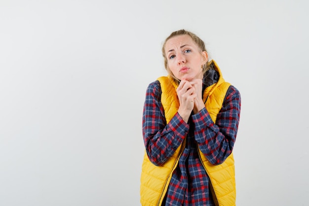 La giovane donna sente freddo stringendo le mani sul petto su sfondo bianco