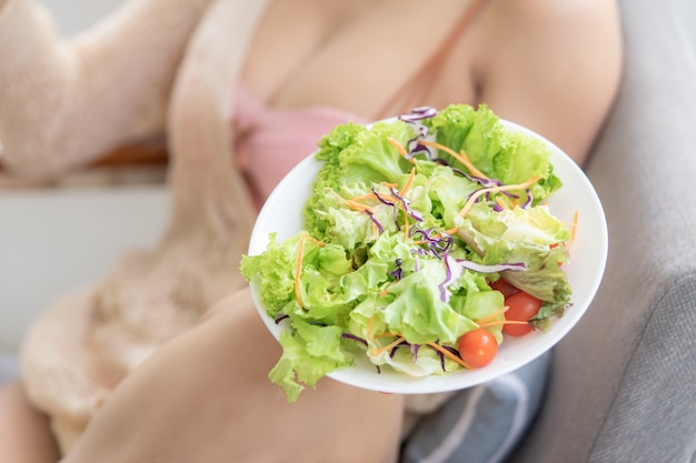 La giovane donna sexy in buona salute sta mangiando l'insalata verde per il concetto sano dell'alimento di stile di vita