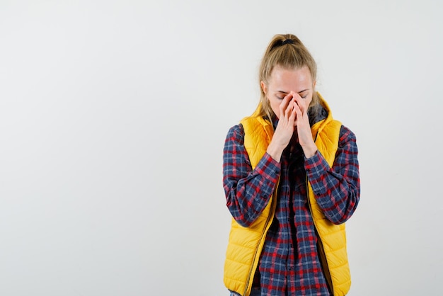 La giovane donna si copre il naso con le mani su sfondo bianco