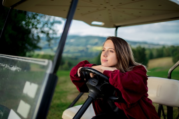 La giovane donna si diverte con l'automobile con errori di golf su un campo in montagne