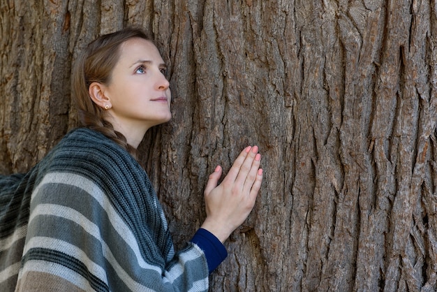 La giovane donna si è appoggiata al tronco di un grande albero