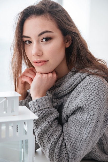 La giovane donna si è vestita in maglione che si siede nel caffè