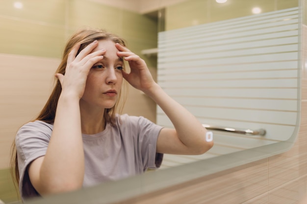 La giovane donna si guarda allo specchio in piedi nel bagno