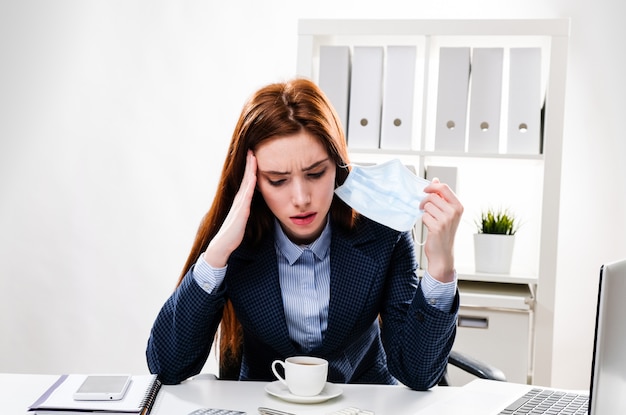 La giovane donna si sentì male al lavoro. La ragazza alla scrivania ha mal di testa.