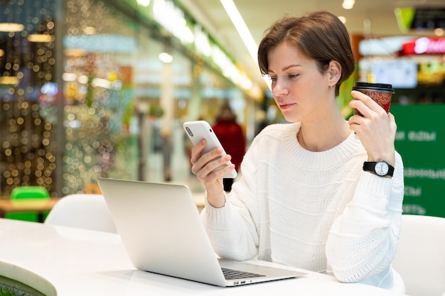 La giovane donna si siede a un computer portatile in un caffè