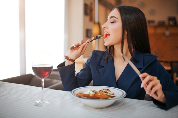 La giovane donna si siede al tavolo nel ristorante e gode di mangiare insalata