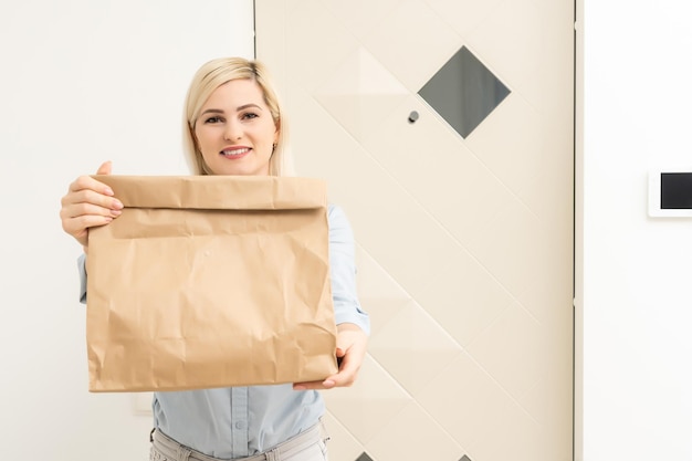 La giovane donna sorridente a casa ha ricevuto un pacco postale, lo shopping online e il concetto di consegna