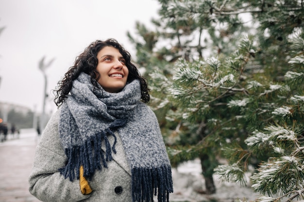 La giovane donna sorridente si trova in un gelido parco invernale innevato.