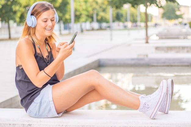 La giovane donna sorridente sta ascoltando la musica con la cuffia