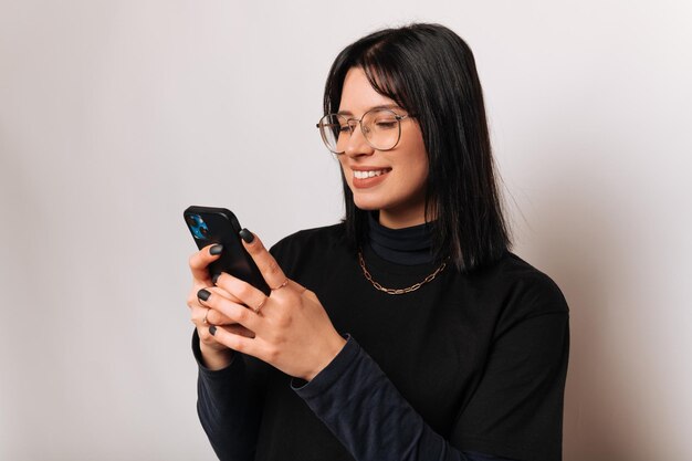 La giovane donna sorridente sta scrivendo un messaggio importante sul suo smartphone