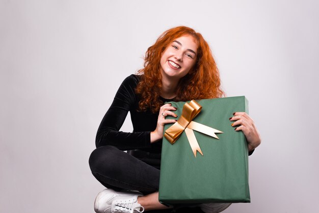 La giovane donna sorridente sta tenendo una parete bianca vicina attuale verde.