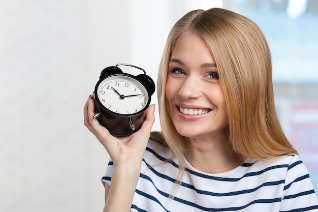 La giovane donna sorridente tiene l'orologio nero