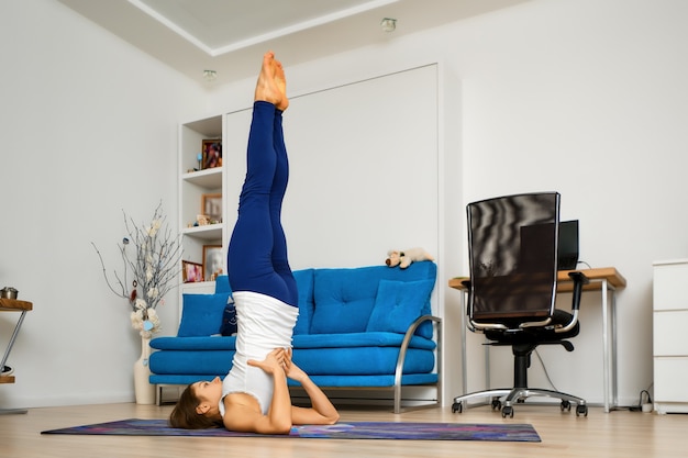 La giovane donna sostiene la posa di yoga delle spalle