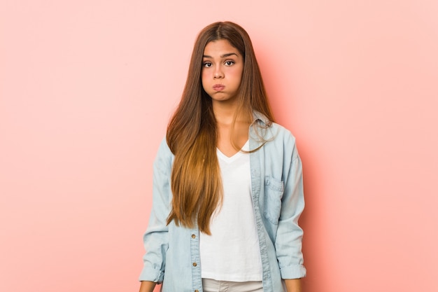 La giovane donna sottile soffia sulle guance, ha un'espressione stanca.