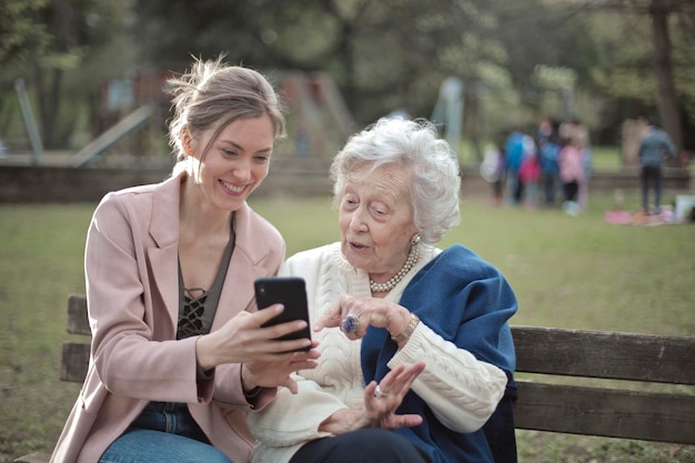 la giovane donna spiega a un'anziana come usare lo smartphone