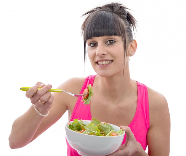 La giovane donna sportiva del brunette mangia l'insalata