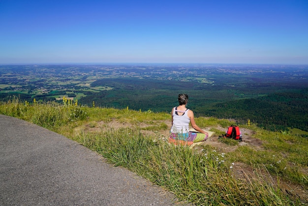 La giovane donna sportiva medita yoga sulla cima della montagna puy de dome in Francia