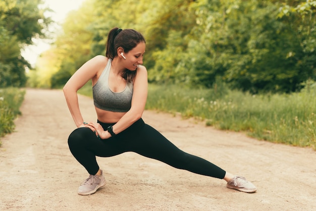 La giovane donna sportiva sta facendo alcuni esercizi di stretching all'aperto nel parco.