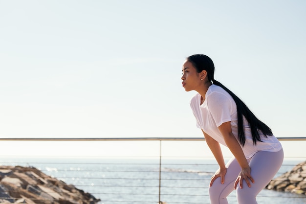 La giovane donna sportiva stanca dallo sforzo riposa per riprendere fiato, concetto di sport e stile di vita attivo