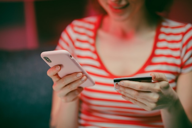 La giovane donna sta acquistando online con una carta di credito mentre era seduto sul divano in salotto.