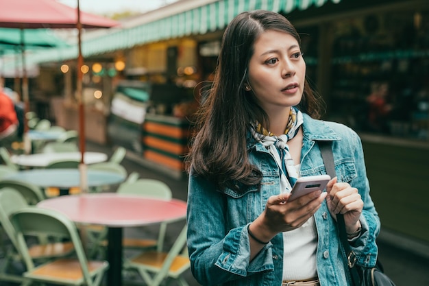 la giovane donna sta camminando e sta usando il suo cellulare per trovare la giusta direzione