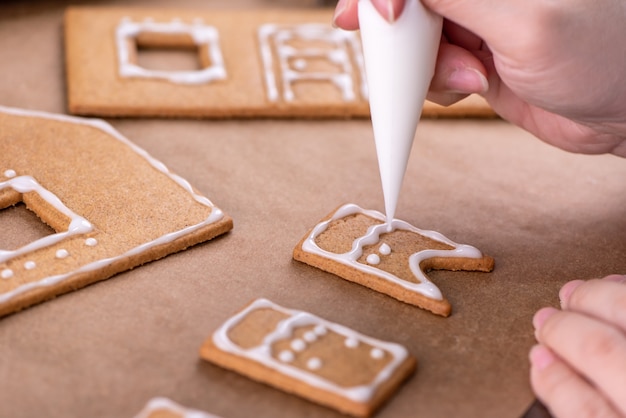 La giovane donna sta decorando i biscotti di pan di zenzero di Natale