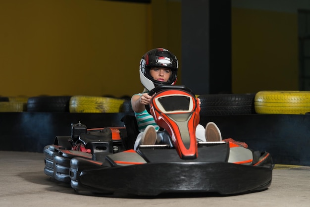 La giovane donna sta guidando l'auto di GoKart con velocità in una pista da corsa del parco giochi Go Kart è un popolare sport motorio per il tempo libero