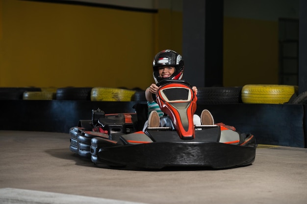 La giovane donna sta guidando l'auto di GoKart con velocità in una pista da corsa del parco giochi Go Kart è un popolare sport motorio per il tempo libero